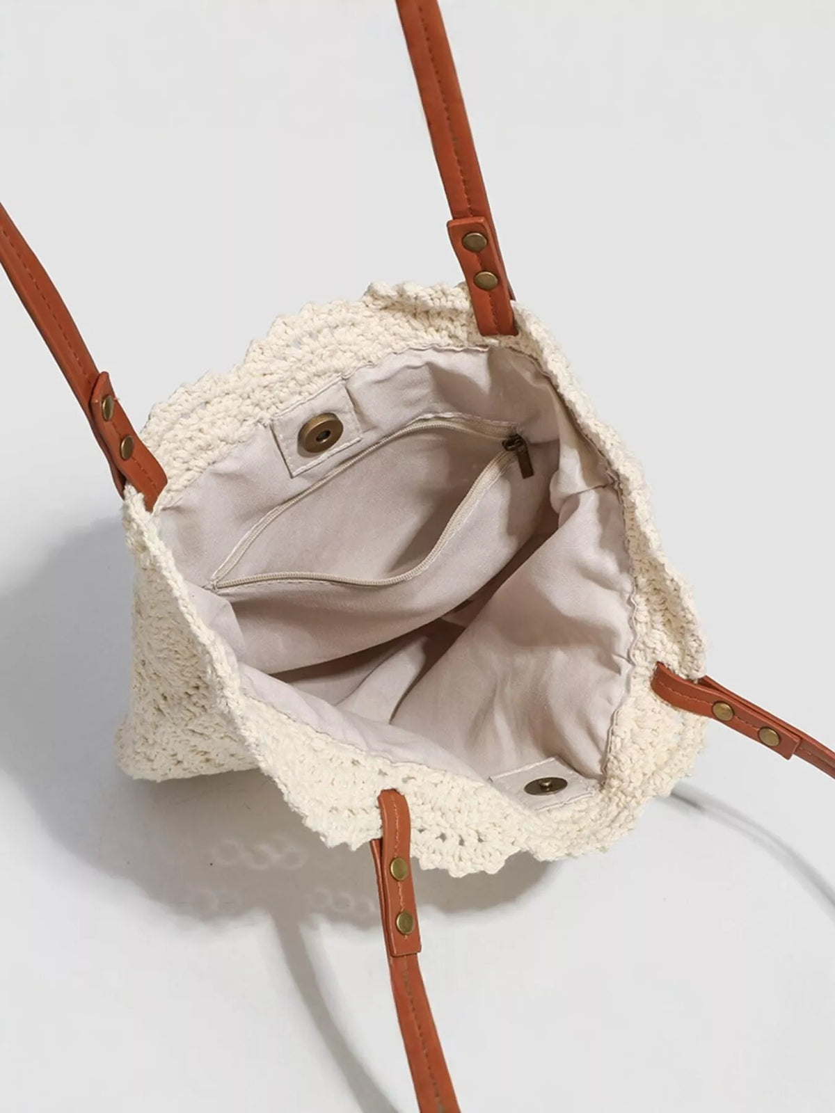 Open ivory crochet tote showing the light lining, inner slip pocket, and snap closure.