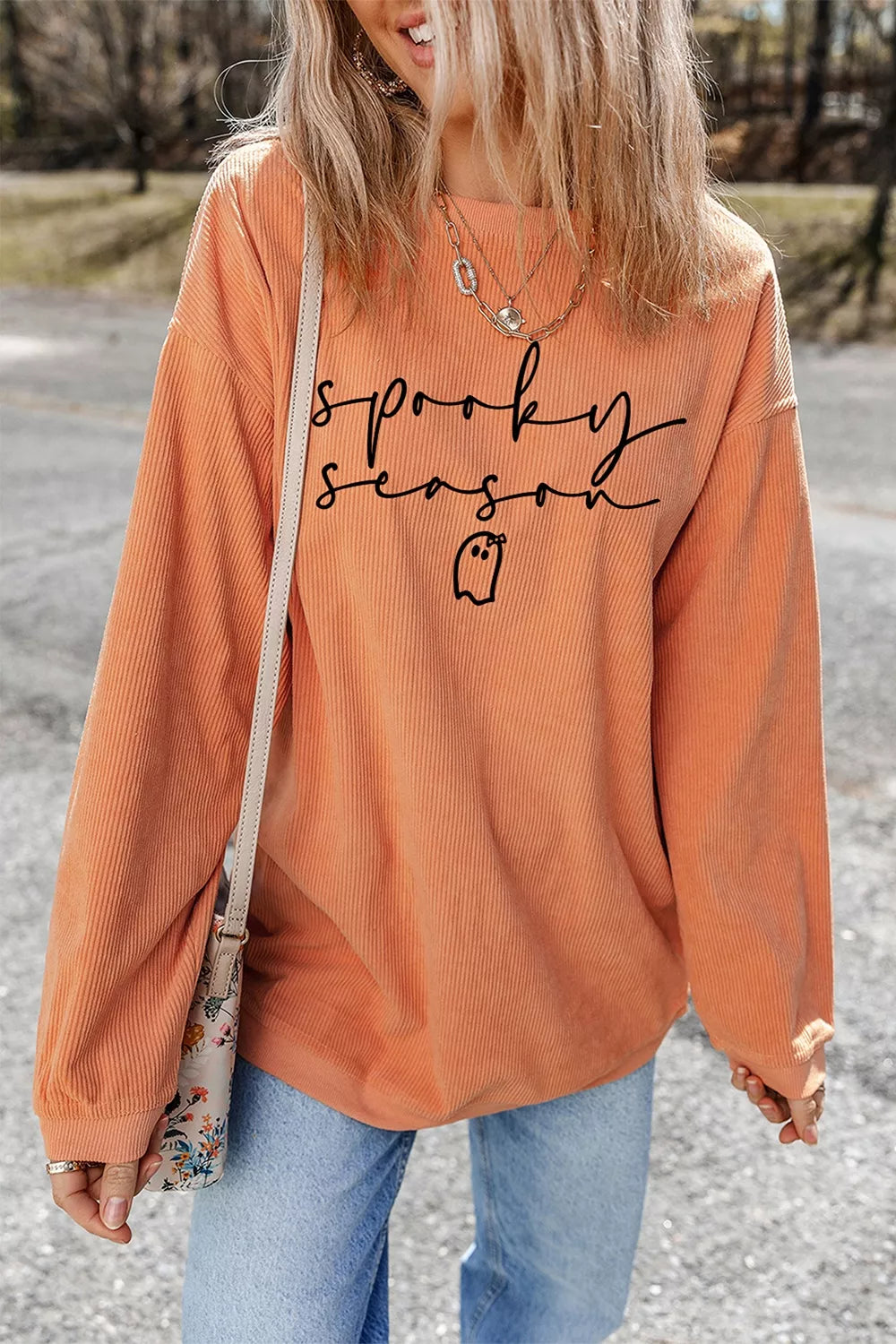Front view of orange ghost graphic sweatshirt with sleeves relaxed