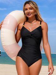 Black one-piece swimsuit with a gathered bust and ruched front, modeled beside an inflatable ring.
