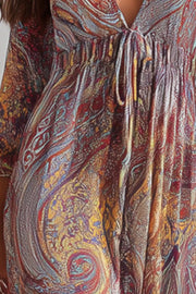 Close-up of the paisley maxi dress's tie neckline and gathered high waist.