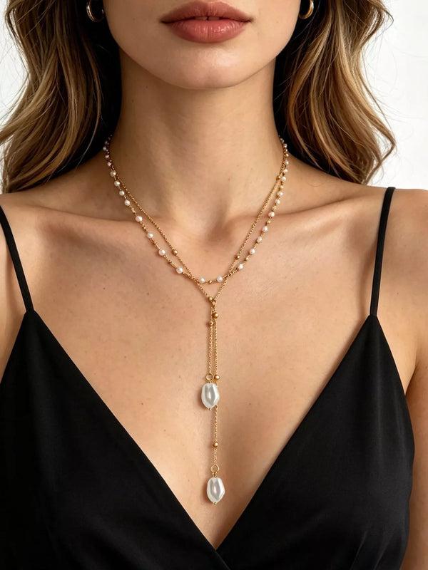Gold-tone layered Y necklace with pearl accents and two drops worn with a black top