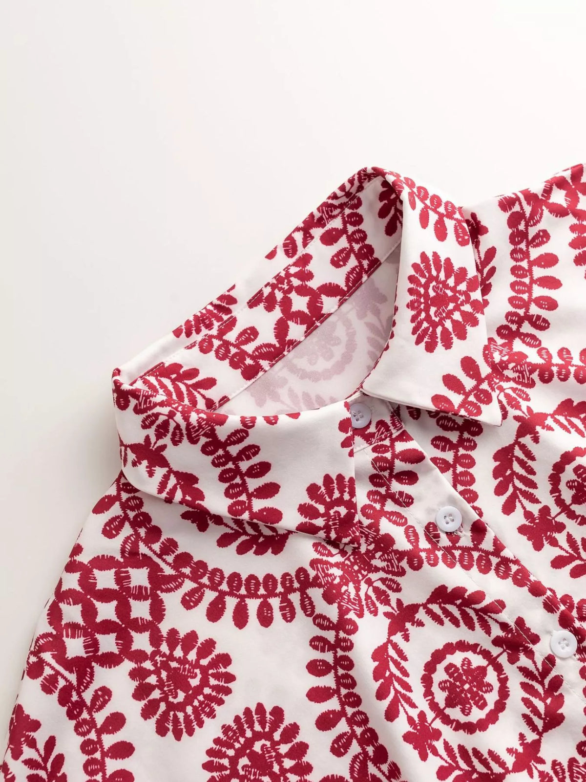 Women's printed tie-waist button-front romper, close-up of red printed fabric
