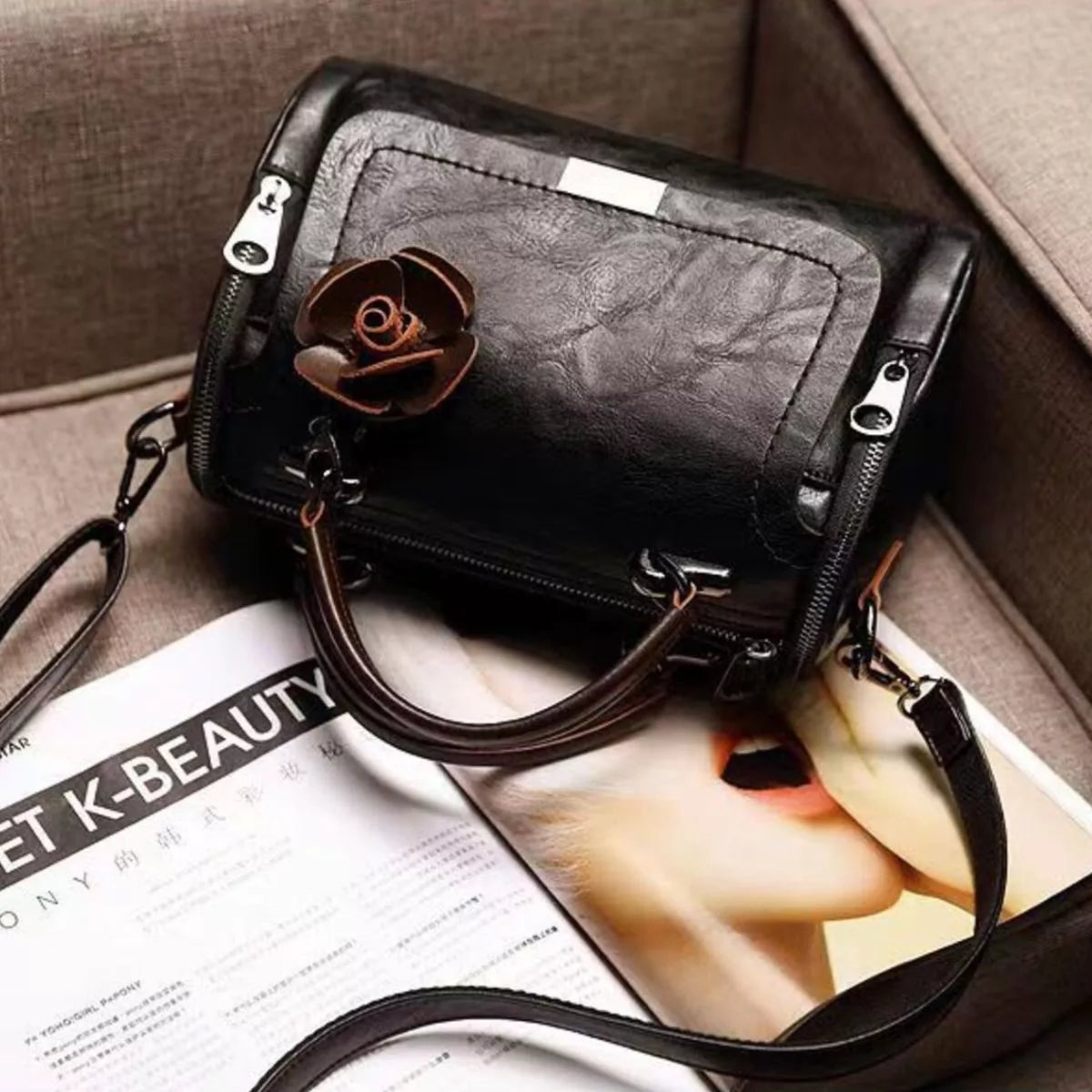 Black flap crossbody bag seen from above with its handles and flower charm