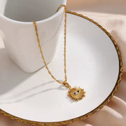 Gold-tone sunburst evil eye necklace displayed on a dish