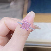 Top view of pink square stone ring on a finger