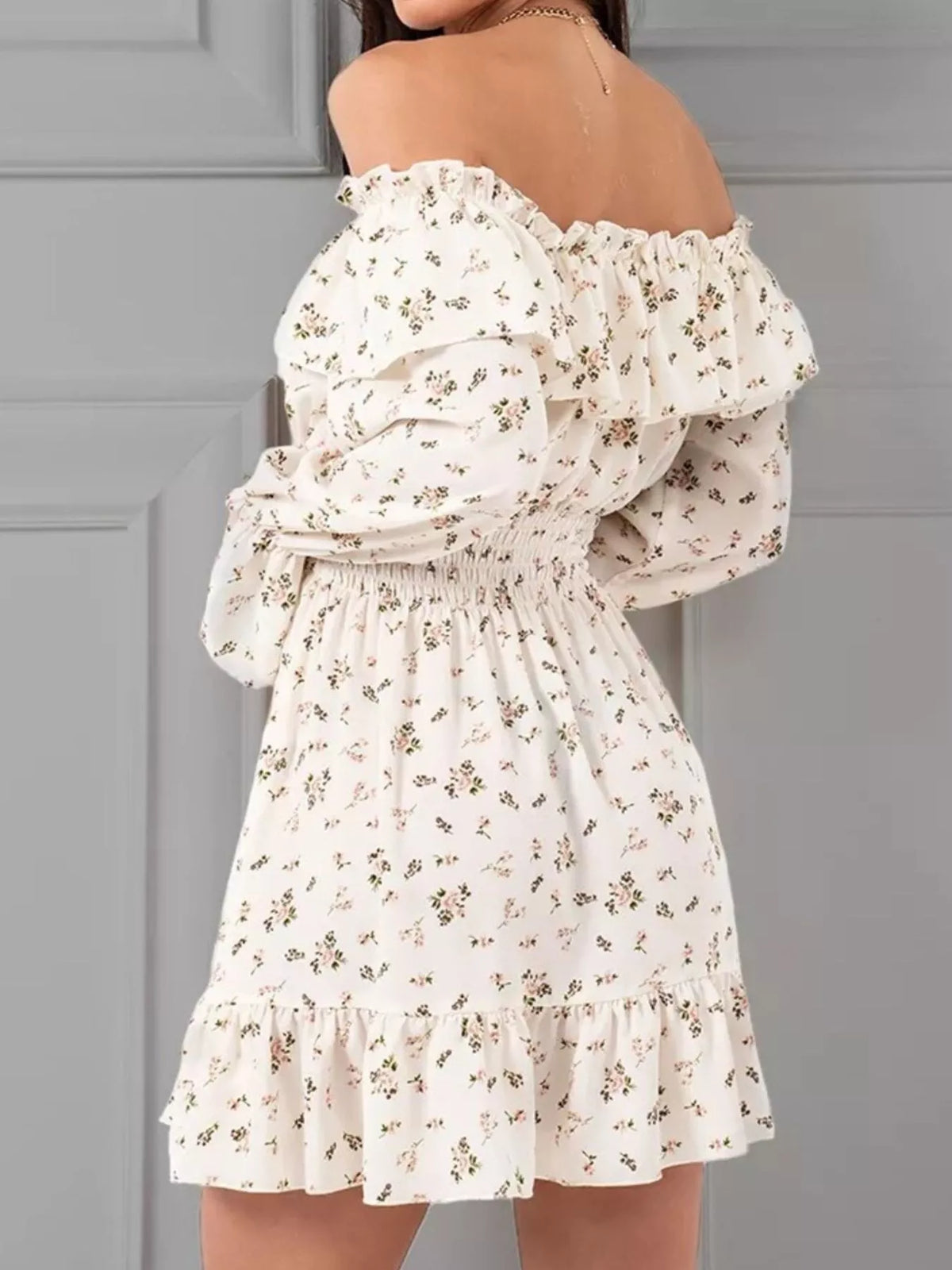 Back view of the white floral off-shoulder dress showing the smocked bodice and long sleeves.