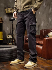 Black cargo pants with buttoned flap thigh pockets modeled with a tan jacket.