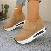 Tan slip-on platform sneakers with thick white soles worn with jeans