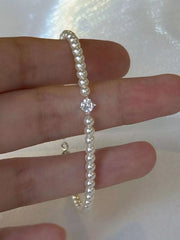 Close detail of the pearl strand and small silver-tone clasp held between fingers.