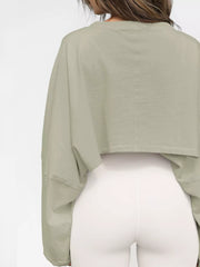 Back view of a pale sage cropped sweatshirt worn with white leggings.