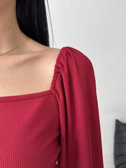 Close-up of gathered sleeve and square neckline on burgundy dress