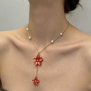 Gold-tone necklace with red flower drops shown from a side angle