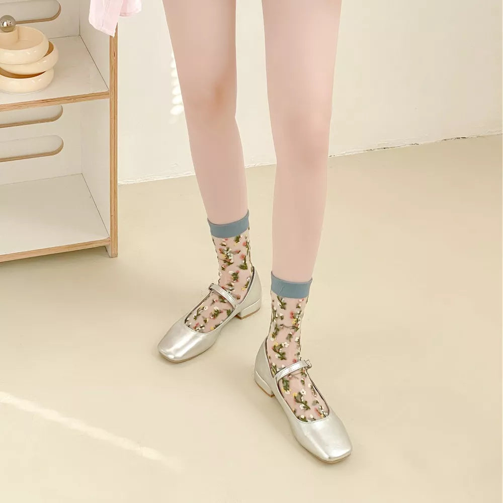 Light floral sheer socks with blue-gray cuffs and toes worn with silver flats