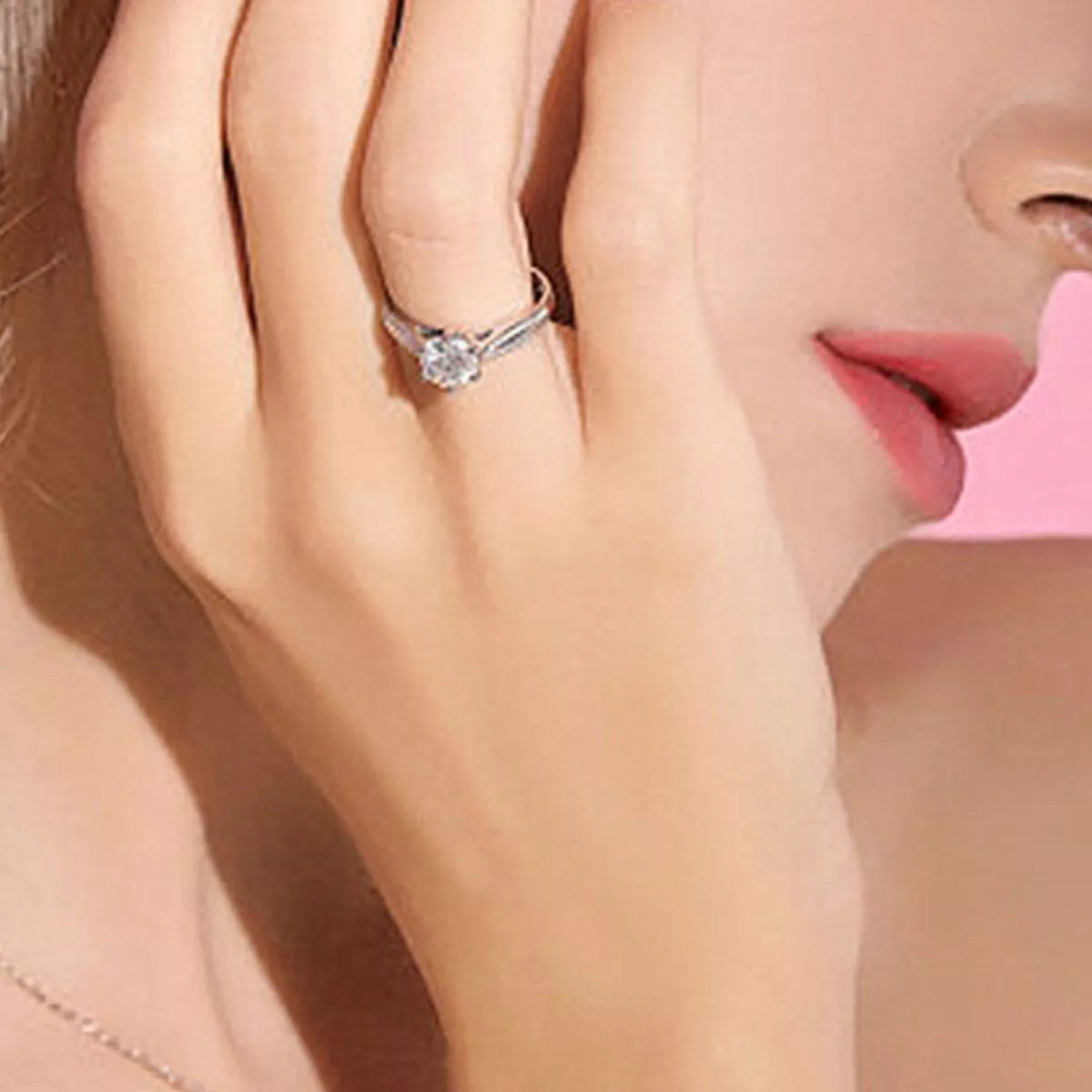 Silver moissanite ring worn on a finger beside the face