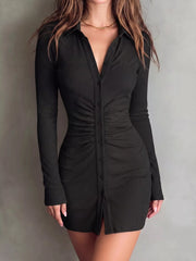 Model stands in black button-front mini dress with gathered center seams.