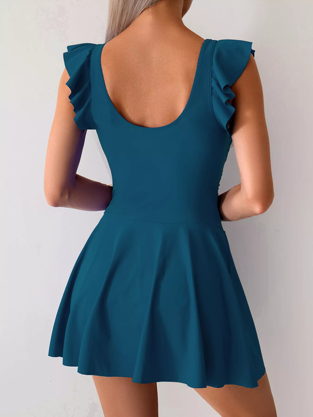Teal swim dress shown from the back with rounded low back