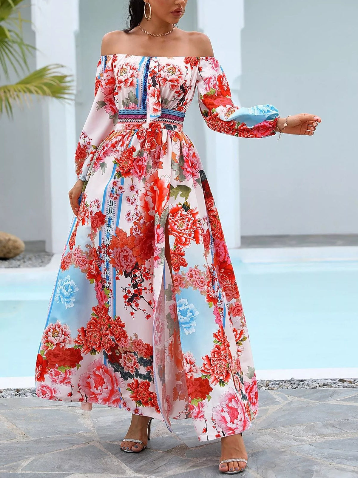 Red and white printed off-shoulder maxi dress with a side slit, shown outdoors.