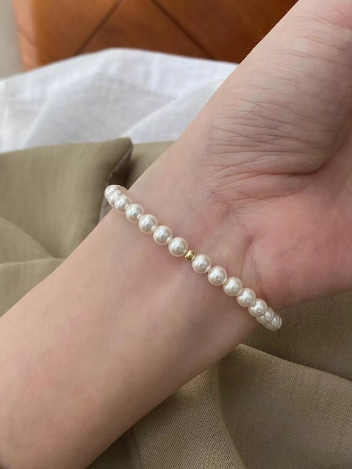 Silver-tone pearl bracelet worn around a wrist against a neutral sleeve.