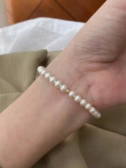 Silver-tone pearl bracelet worn around a wrist against a neutral sleeve.