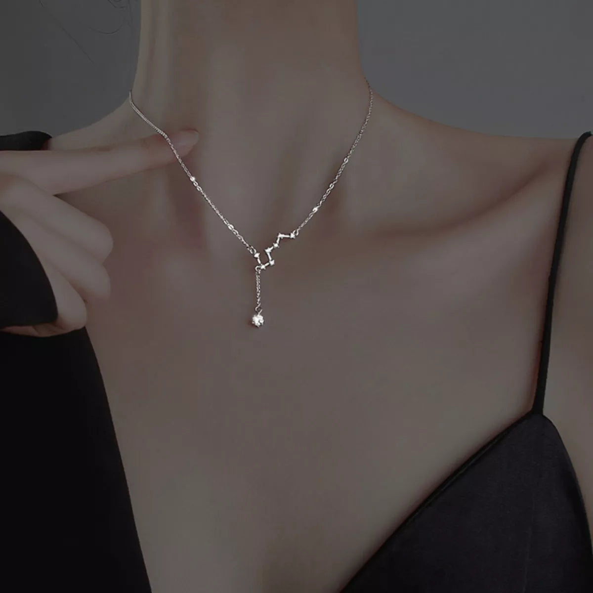 Model wearing a delicate silver star necklace and adjusting the chain
