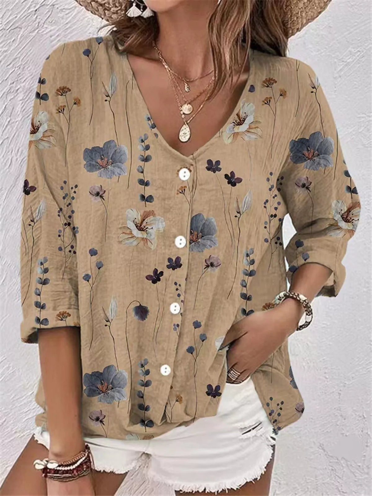 Model wearing beige floral V-neck button-down blouse with white shorts.