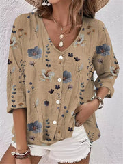Model wearing beige floral V-neck button-down blouse with white shorts.