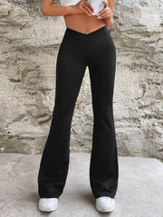 Black V-waist flared pants shown straight on with the model's hands raised above the waist.