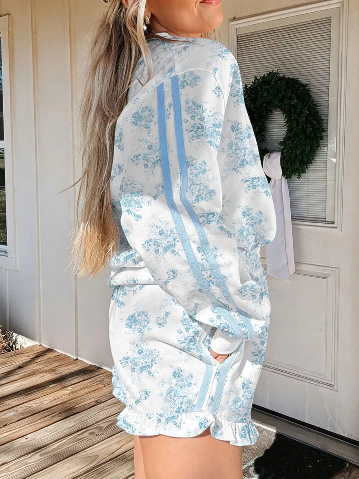 Side view of white floral sweatshirt and ruffle-hem shorts set