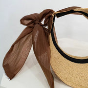 Close-up of coffee-brown ribbon bow and woven straw visor edge