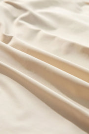 Close-up of smooth ivory skort fabric folded into soft drapes.