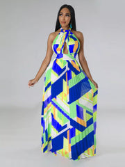 Model holding both sides of the pleated skirt of a blue, lime and white halter maxi dress.