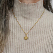 Gold-tone evil eye sunburst pendant necklace worn over a ribbed top