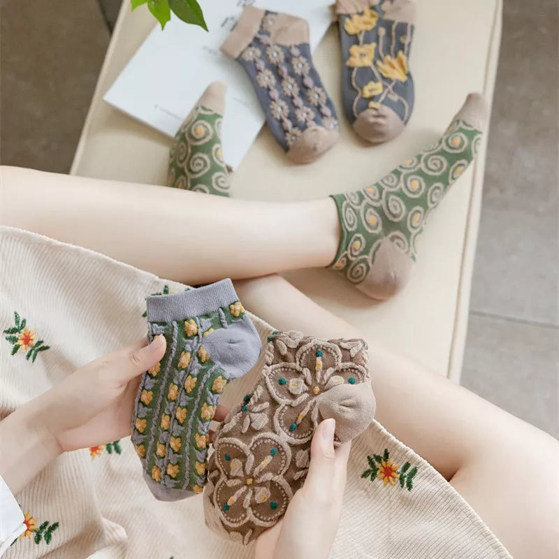 Green spiral socks worn while holding folded floral pairs from the ankle sock set