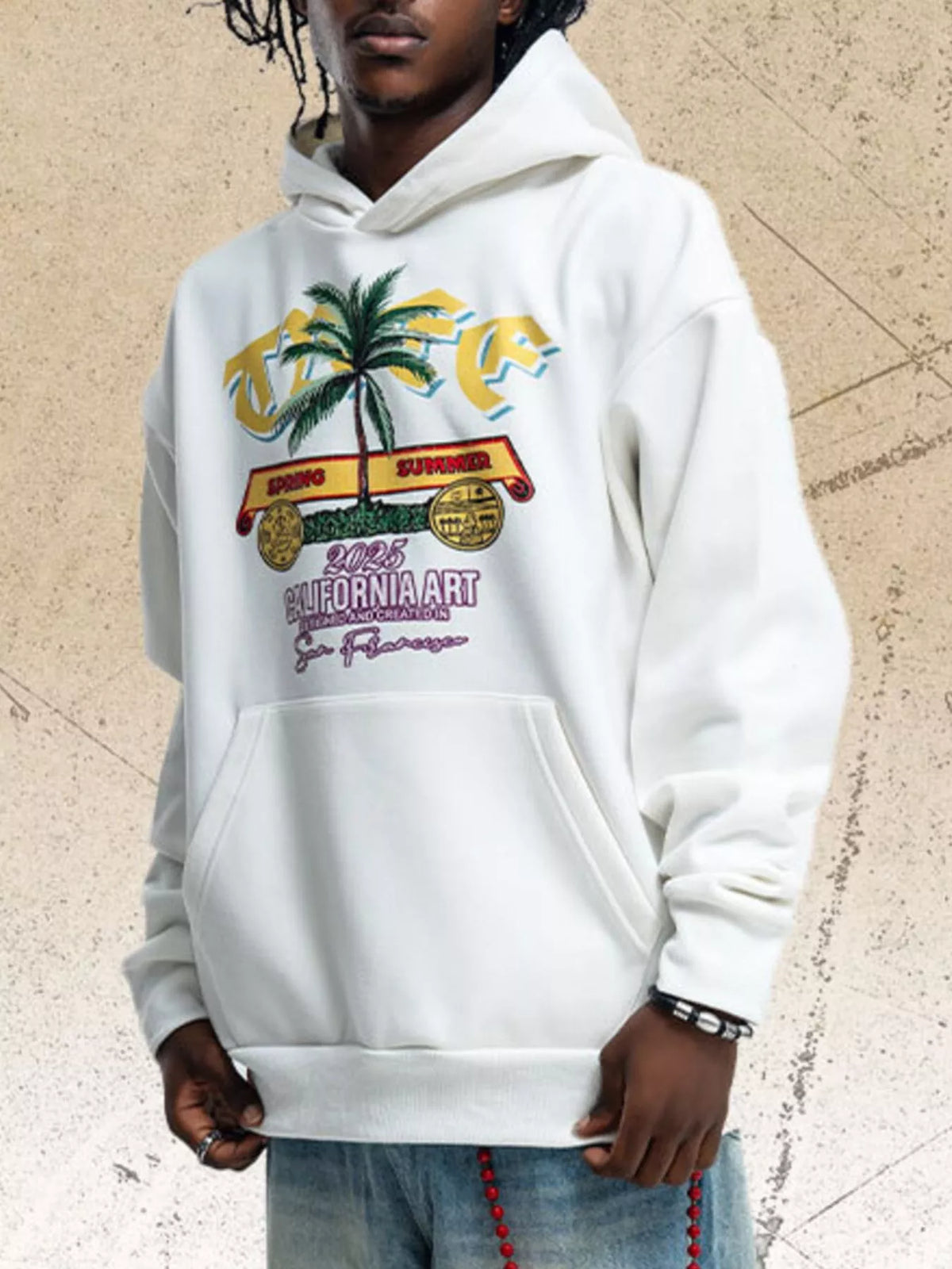 Model wearing white graphic hoodie with colorful palm tree chest print