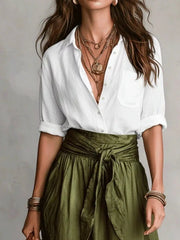 Close view of white button-down shirt with an olive green wrap-style tie-waist skirt.
