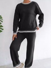 Black sweater and pants set shown with one knee bent and a hand at the hip.