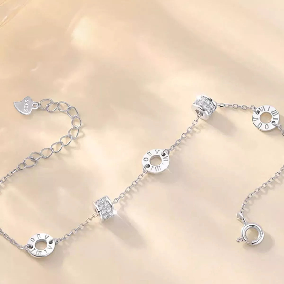 Close-up of circular and rectangular details along the silver chain bracelet