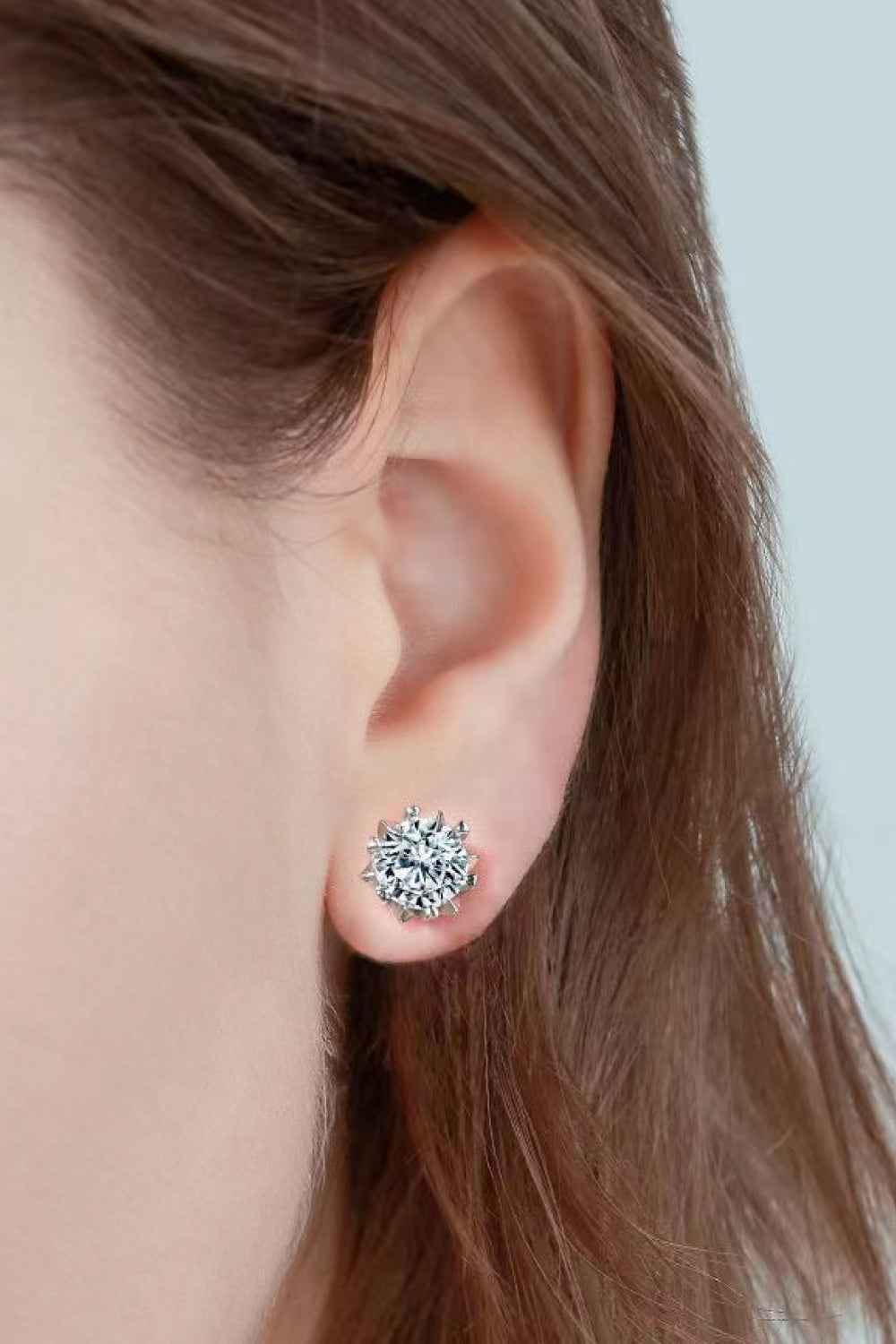 Close-up of a round clear-stone stud earring worn on an ear