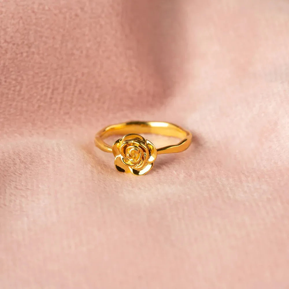 Close-up of the sculpted gold rose ring resting against skin