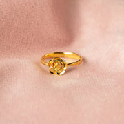 Close-up of the sculpted gold rose ring resting against skin