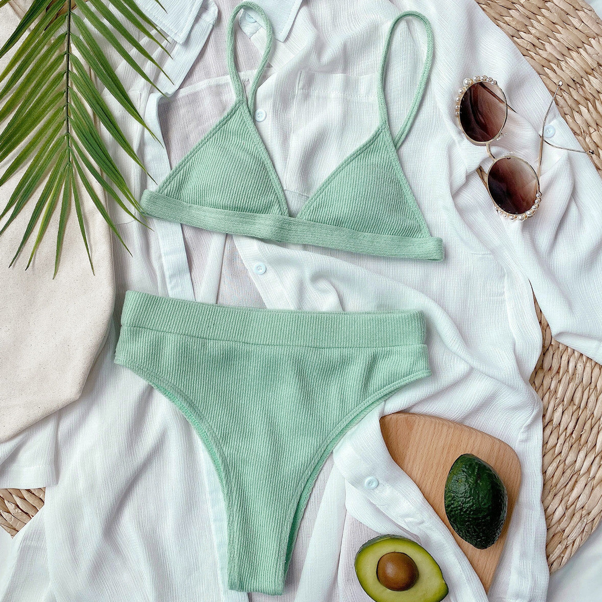 Mint green ribbed bikini set laid flat with sunglasses and avocado dish
