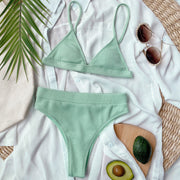 Mint green ribbed bikini set laid flat with sunglasses and avocado dish