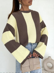 Model wearing oversized sweater with wide cream and dark brown vertical colour blocks and flared sleeves