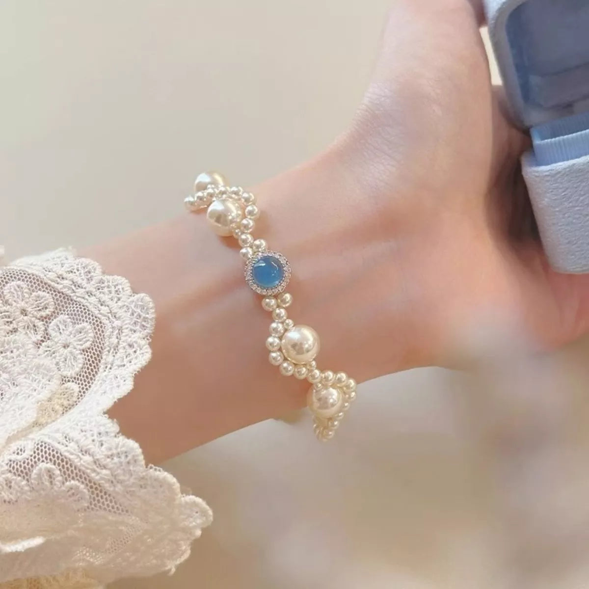 Close-up of pearl bracelet with blue center stone worn on wrist