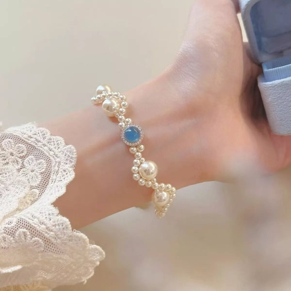 Close-up of pearl bracelet with blue center stone worn on wrist