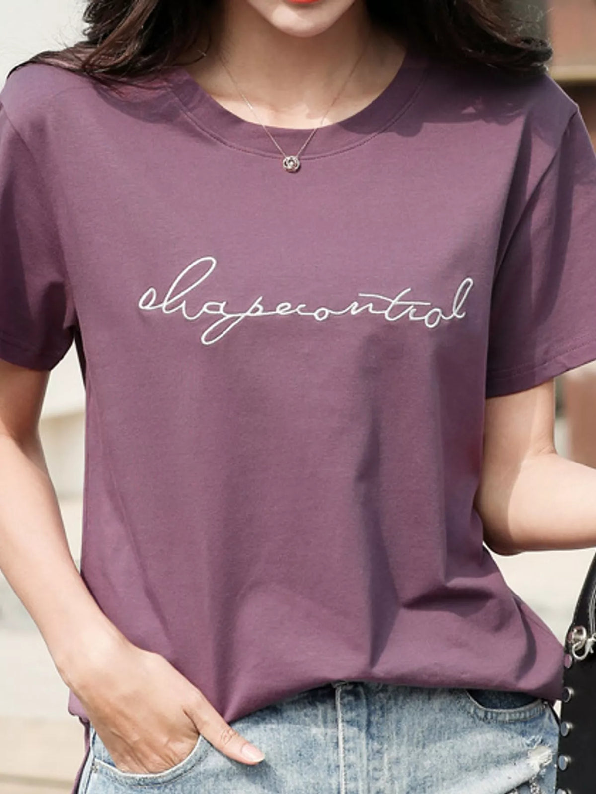 Model wearing a purple crew-neck T-shirt with embroidered script lettering