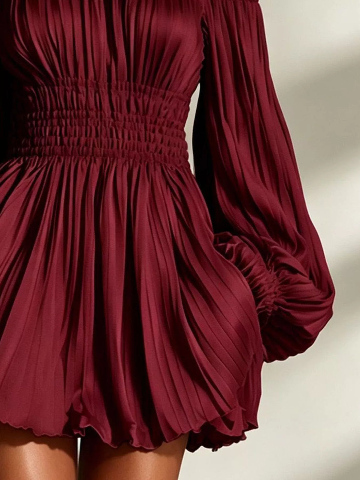 Close view of burgundy dress's pleated bodice, gathered waist, and sleeve