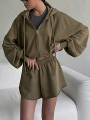 Olive zip hoodie and shorts, seated pose with cup