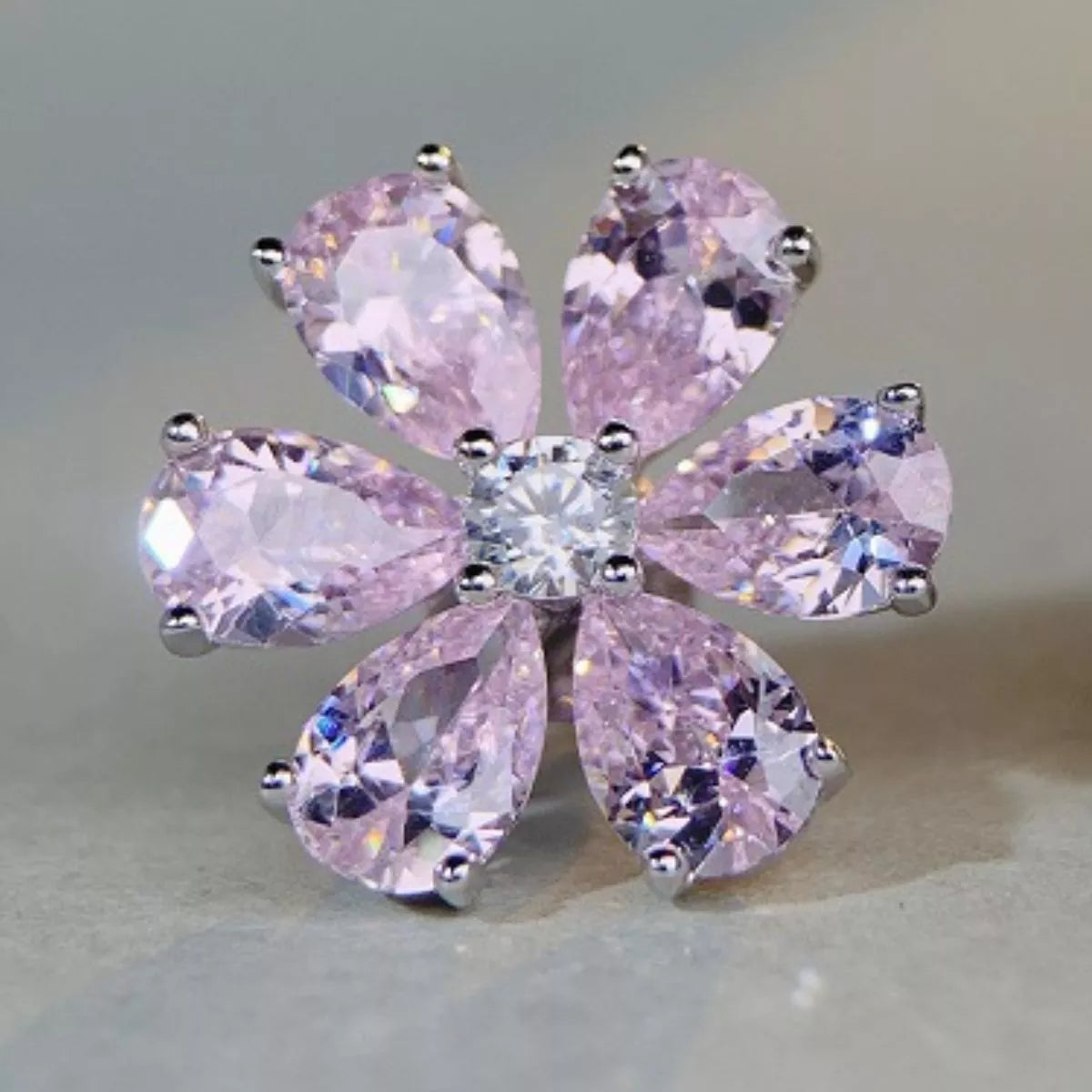 Close view of pink flower stud earring showing six faceted petals and clear centre