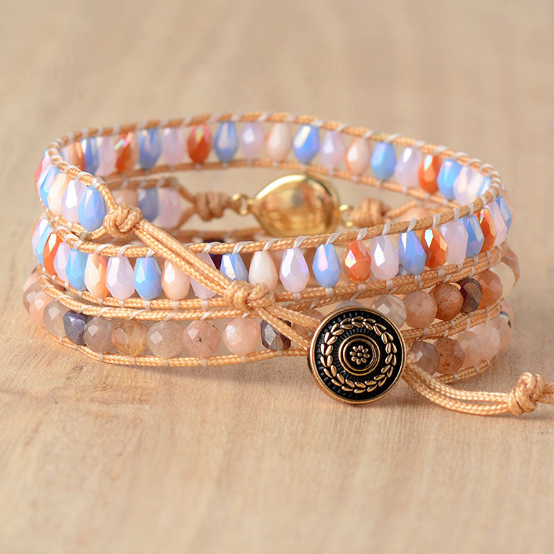 Multicolored beaded wrap bracelet with a round dark ornamental button clasp displayed on wood